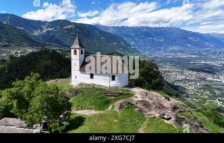 St. Hippolyt a Naraun, Südtirol, Italien 04. Juli 2024: Hier der Blick auf das Kirchlein St Hippolyt in Naraun bei Tisens, prähistorischer Siedlungsplatz, hier aus der Luft, im Hintergrund das Etschtal mit dem Meraner Kessel, Merano, Lana, Vigiljoch und Texelgruppe Tourismus, Hochburg, Hotspot, vagabondo, eren **** St Hippolyt a Naraun, alto Adige, Italia 04 luglio 2024 qui la vista della chiesetta di Sant'Ippolito a Naraun vicino a Tisens, luogo di insediamento preistorico, qui dall'alto, sullo sfondo della Valle dell'Adige con il bacino del Merano, Merano, Lana, Vigiljoch e Texel turismo di gruppo Foto Stock