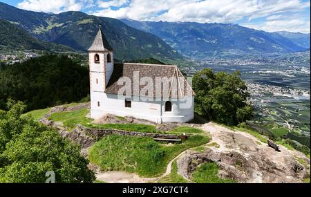 St. Hippolyt a Naraun, Südtirol, Italien 04. Juli 2024: Hier der Blick auf das Kirchlein St Hippolyt in Naraun bei Tisens, prähistorischer Siedlungsplatz, hier aus der Luft, im Hintergrund das Etschtal mit dem Meraner Kessel, Merano, Lana, Vigiljoch und Texelgruppe Tourismus, Hochburg, Hotspot, vagabondo, eren **** St Hippolyt a Naraun, alto Adige, Italia 04 luglio 2024 qui la vista della chiesetta di Sant'Ippolito a Naraun vicino a Tisens, luogo di insediamento preistorico, qui dall'alto, sullo sfondo della Valle dell'Adige con il bacino del Merano, Merano, Lana, Vigiljoch e Texel turismo di gruppo Foto Stock