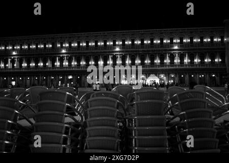 Sedie da caffè impilate in fila di notte, Cafe Florian con l'orchestra che suona in Piazza San Marco Foto Stock