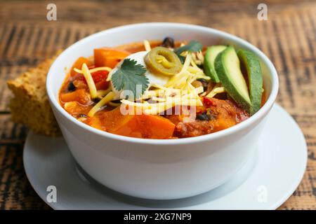 Peperoncino di zucca invernale vegano, servito con pane di mais Foto Stock