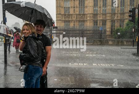 Le persone corrono per la copertura dalle forti piogge di Westminster a Londra . Data foto: Domenica 7 luglio 2024. Foto Stock