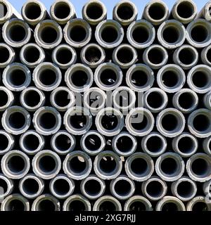 Tubi in calcestruzzo impilati su terreni dell'impianto. Foto Stock