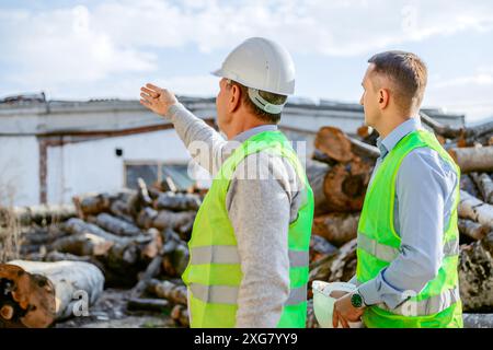 Due operai edili che indossano giubbotti di sicurezza stanno discutendo di un cantiere. Foto Stock