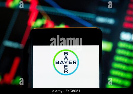 In questa immagine, la multinazionale farmaceutica tedesca, il logo Bayer AG (ETR: BAYN) visualizzato su uno smartphone con un grafico indice di borsa economica sullo sfondo. Foto Stock