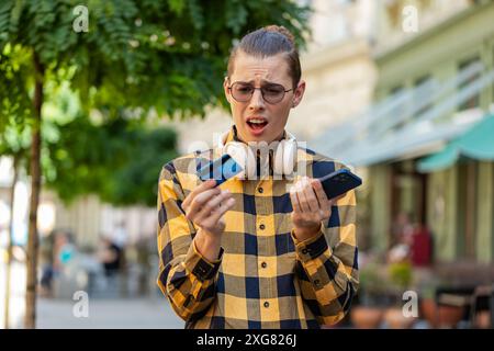 Scioccato uomo caucasico che cerca di pagare lo shopping online con smartphone bloccato carta di credito. Il giovane turista che si trova in strada che compra la banca si rifiuta problema di pagamento senza successo mancanza di saldo monetario. Foto Stock