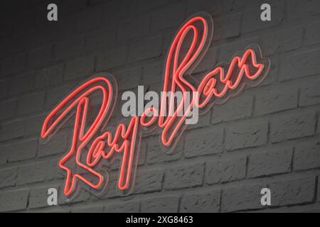 Un luminoso cartello al neon RayBan si illumina su una parete di mattoni, rendendolo un'immagine perfetta per immagini eleganti e alla moda Foto Stock