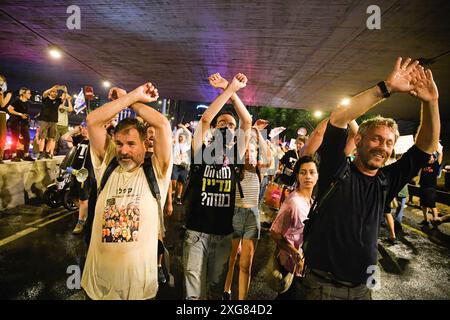 Tel Aviv, Israele. 6 luglio 2024. I manifestanti attraversano le mani in alto mentre bloccano l'autostrada Ayalon durante la dimostrazione. Oltre 100.000 israeliani hanno manifestato a Kaplan con le famiglie degli ostaggi contro il primo ministro Benjamin Netanyahu, chiedendo un accordo immediato con gli ostaggi e il cessate il fuoco, durante la manifestazione, i manifestanti hanno bloccato l'autostrada Ayalon e sono stati dispersi da un cannone d'acqua della polizia. Credito: SOPA Images Limited/Alamy Live News Foto Stock