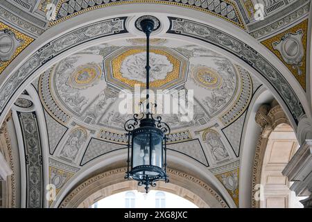 Budapest, Ungheria, 18 maggio 2024. Un motivo circolare simmetrico di angelo cherubico su un soffitto con lampada del Teatro dell'Opera in Ungheria. Dettagli esterni di Foto Stock