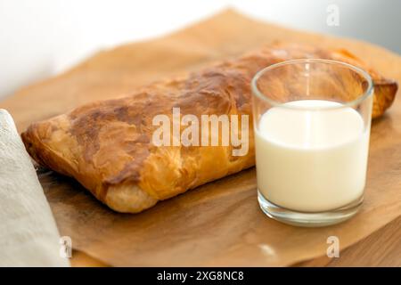 pasticceria dolce fatta in casa con pasta sfoglia con crosta croccante e un bicchiere di latte. torte calde fatte in casa Foto Stock