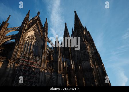 Una splendida vista della facciata gotica di una cattedrale storica, che mostra intricati dettagli architettonici e guglie svettanti contro un cielo limpido e blu Foto Stock