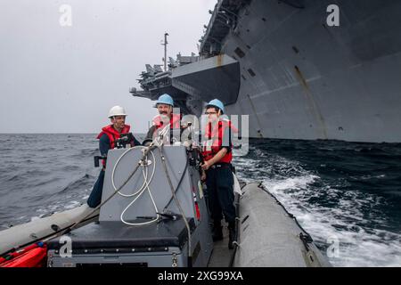 EAST CHINA SEA (27 giugno 2024) i marinai statunitensi gestiscono un gommone a scafo rigido nelle acque circostanti la portaerei classe Nimitz USS Theodore Roosevelt (CVN 71), 27 giugno 2024. La Theodore Roosevelt, nave ammiraglia del Carrier Strike Group Nine, sta conducendo operazioni di routine nell'area delle operazioni della 7th Fleet. La U.S. 7th Fleet è la più grande flotta numerata della Marina degli Stati Uniti, e interagisce e opera regolarmente con alleati e partner nel preservare una regione indo-pacifica libera e aperta. (Foto della Marina degli Stati Uniti dello specialista di comunicazione di massa Seaman Ryan Holloway) Foto Stock