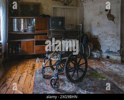 Sedia a rotelle vuota in una vecchia casa abbandonata. Foto Stock
