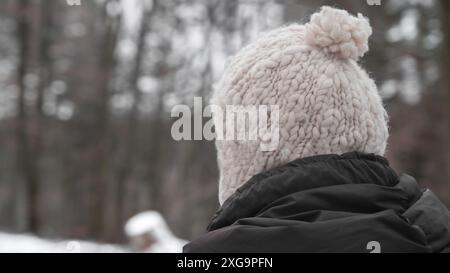 La donna indossa un caldo berretto di lana mentre va a fare una passeggiata in inverno Foto Stock