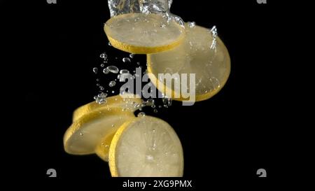 Limoni che cadono in acqua. Sfondo isolato Foto Stock