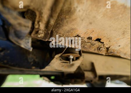 Operazioni di riparazione e saldatura della carrozzeria da eseguire in primo piano. Ruggine su una vecchia macchina grigia. Foro di ruggine su una vecchia superficie metallica verniciata usurata Foto Stock