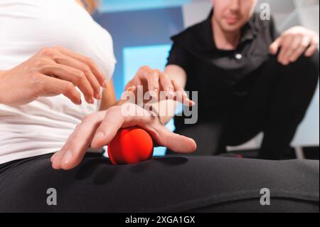 Il fisioterapista insegna l'auto-massaggio con palline rosse, paziente con lesioni alle gambe. Trattamento delle lesioni sportive. Uso pratico. Concetto di riabilitazione Foto Stock