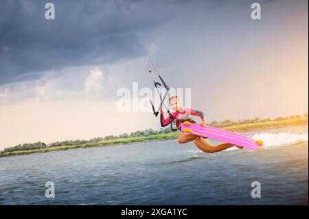 Una giovane kitesurfer cavalca le onde facendo un trucco. Sport acquatici. kitesurfing Foto Stock