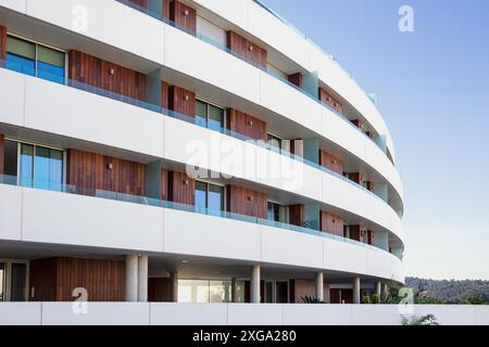 Moderno edificio di appartamenti con facciata curva. Calcestruzzo bianco, legno e vetro. Spazio di copia Foto Stock