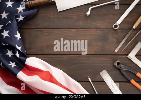 Vista dall'alto della bandiera americana e delle attrezzature su un piano portapaziente in legno con spazio per la copia. Background concettuale del giorno del lavoro Foto Stock