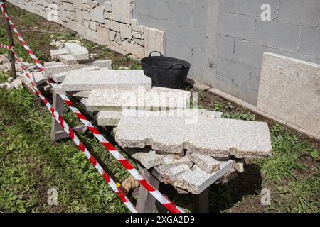 Parete di blocco di cenere rivestita con lastre di granito in cantiere esterno. Decorazione della parete Foto Stock