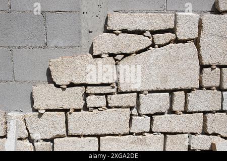 Particolare della parete del blocco di Cinder essendo rivestita con lastre di granito in cantiere esterno. Decorazione della parete Foto Stock