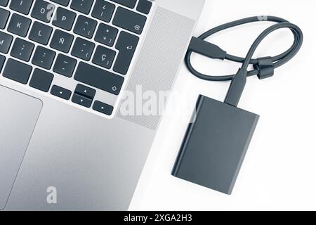 Disco rigido esterno collegato a un moderno computer portatile. Vista dall'alto Foto Stock