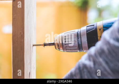 Fai da te l'handyman a casa sta usando un cacciavite cordless per l'avvitamento Foto Stock