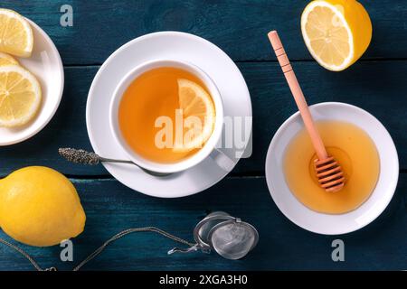 Tè al limone con miele, sgonatura piatta su uno sfondo rustico di legno. Gustosa bevanda calda agli agrumi per le fredde giornate invernali Foto Stock