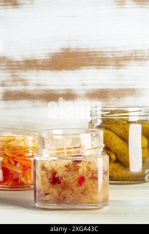 Sauerkraut, kimchi e sottaceti in vasetti di mason, cibo in scatola su un rustico sfondo di legno con un posto per il testo Foto Stock