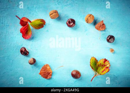 Sfondo autunnale con foglie e castagne vivaci, foto in orizzontale su blu con un posto per il testo, un modello di design per un banner o. Foto Stock