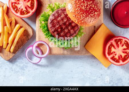 Ingredienti del hamburger su un asse di legno, sopra il getto piatto con un posto per il testo. Hamburger e patatine fritte, sparate dall'alto con spazio copia Foto Stock