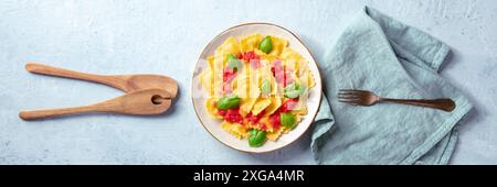 Ravioli italiani con salsa di pomodoro rosso e basilico, panorama a cielo piano con forchetta e cucchiai di legno Foto Stock