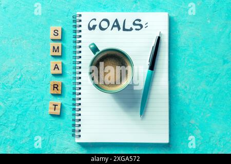 Concetto di Smart Goals. Un blocco note con la parola scritta a mano, per scrivere un piano o un elenco, uno scatto orizzontale su uno sfondo blu brillante con una Foto Stock