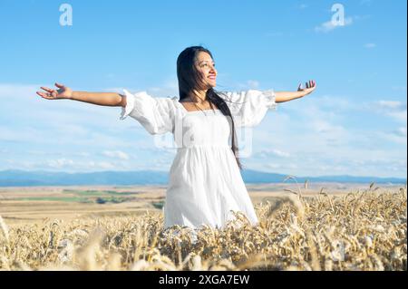 Ritratto di una giovane donna felice in un vestito bianco, su un campo di grano. Concetto di stile di vita e felicità. Donna a braccia aperte, foto di alta qualità Foto Stock