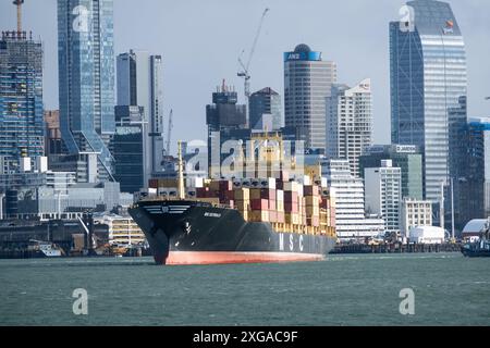 Auckland, nuova Zelanda - 23 luglio 2023: Una nave portacontainer lascia il porto commerciale di Auckland nella più grande città della nuova Zelanda con il cielo del CBD Foto Stock