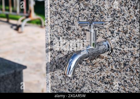 moderno rubinetto esterno in metallo con acqua potabile pulita nel parco sulla strada della città in estate Foto Stock