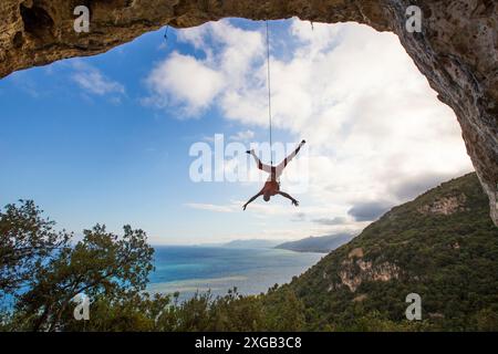 Arrampicatore sospeso su corda dal soffitto di roccia, finale Ligure, Liguria, Italia Foto Stock