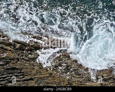 Spruzzi d'acqua sulla costa frastagliata dell'Italia. Giornata di sole con increspature bianche viste dall'alto. Foto Stock