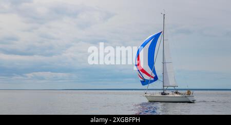 Yacht che naviga sulle onde del mare aperto. Paesaggio nautico con barca a vela - yacht da crociera in barca a vela spinnaker che partecipa alla regata. Ro Foto Stock