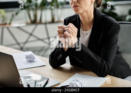 Una donna di mezza età in difficoltà, seduta a una scrivania con un notebook, che soffre di un crollo mentale. Foto Stock