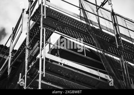 Costruzione di edifici residenziali in bianco e nero. Industria abitativa. Rete protettiva per costruzioni edili. Case a più piani incompiute. Immobili. Foto Stock