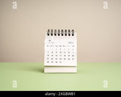 Un calendario da scrivania di luglio 2024 per l'organizzatore, da pianificare e ricordare isolato su tavolo verde e sfondo bianco, stile minimal. Piccolo calendario bianco Foto Stock