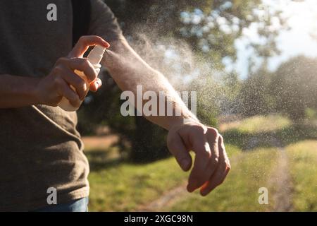 Prevenzione contro il morso di zanzare durante il sole del giorno estivo. L'uomo sta applicando repellente per insetti sulla sua mano. Foto Stock