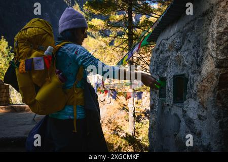 Una donna caucasica, escursionista, getta via la bottiglia di plastica al punto di raccolta ufficiale sul percorso di trekking del campo base dell'everest sulle montagne dell'Himalaya Foto Stock