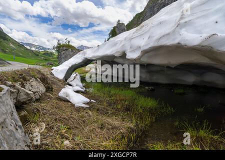 Riposo dalla valanga, neve sciolta nelle Alpi del Vorarlberg fare tunnel nella valanga, neve sulle montagne si scioglie, campi di neve su pendii ripidi Foto Stock