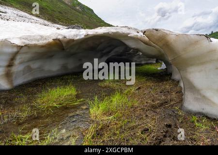 Riposo dalla valanga, neve sciolta nelle Alpi del Vorarlberg fare tunnel nella valanga, neve sulle montagne si scioglie, campi di neve su pendii ripidi Foto Stock