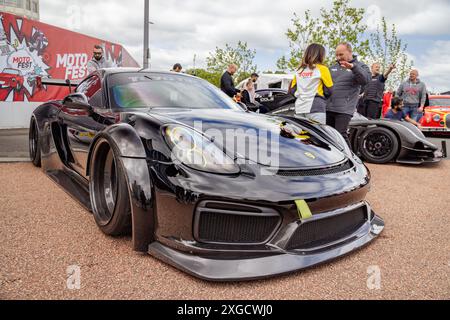 Tre quarti di vista di una Porsche Cayman dotata di un kit per lo styling della carrozzeria parcheggiata in un ambiente urbano durante il Coventry Motofest. Foto Stock