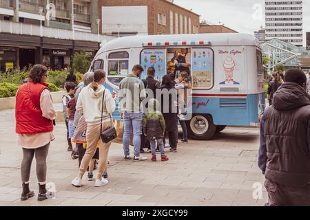 La gente fa la fila pazientemente per acquistare un gelato da un pulmino in un centro commerciale urbano. Foto Stock