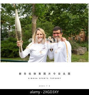 (240708) -- PECHINO, 8 luglio 2024 (Xinhua) -- Torchbearers Rodolphe Delord (R), direttore generale dello zoo di Beauval e navigatore francese Maud Fontenoy posa per le foto con due panda giganti Huan Lili e Yuan Dudu dietro di loro durante la staffetta della fiamma olimpica di Parigi 2024 allo zoo di Beauval a Saint-Aignan, Francia centrale, 8 luglio 2024. (Zoo Parc de Beauval/handout via Xinhua) Foto Stock