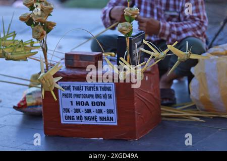 Hoi An, Vietnam 7 luglio 2024: Il falegname vende la cavalletta, fatta dalla tessitura dell'erba. la tessitura dell'erba è un'abilità tradizionale di tessitura artistica. Foto Stock